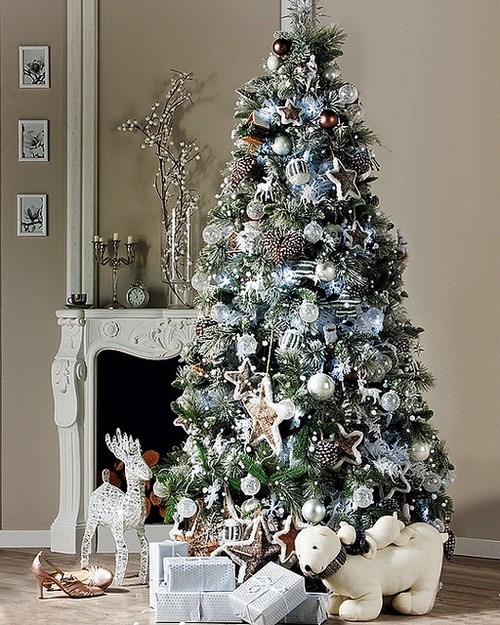 a Christmas tree with star, ball, snowflake and other ornaments in silver and white, with ribbons and garlands