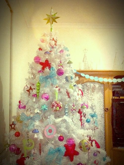 a pure white Christmas tree with colorful ornaments in various shapes and looks plus a tar topper will brighten up your space