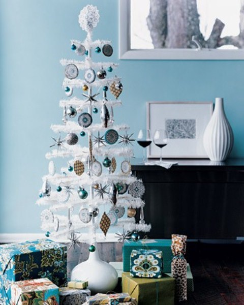 a white tabletop Christmas tree with silver and blue ornaments, with a lace topper and some mini ornaments