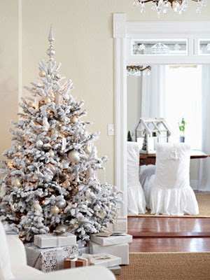 a snowy Christmas tree with lights and white and sivler ornaments to match its frozen beauty