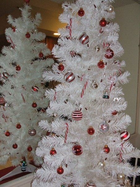 a white Christmas tree with white and red ornaments that contrast it and create a bold and bright festive ambience