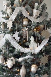 a muted Christmas tree with lights, silver, white and gold ornaments, paper garlands, shiny snowflakes and other stuff