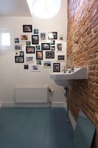 Combination of a modern gallery wall with a brick wall is a stylish solution for creative interiors.