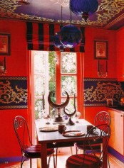 a colorful Moroccan dining room with navy patterns and a patterned ceiling, chic furniture and patterned chairs, navy pendant lamps and half moons