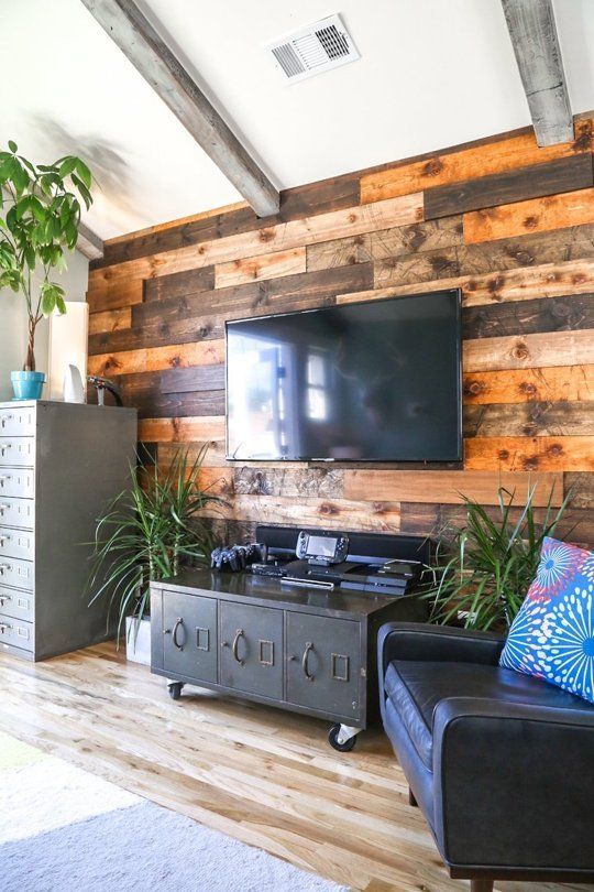 A weathered and stained wood accent wall softens the industrial inspired living room with vintage touches