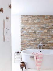 an earthy colored faux stone accent wall is a gorgeoys way to spruce up a neutral contemporary bathroom