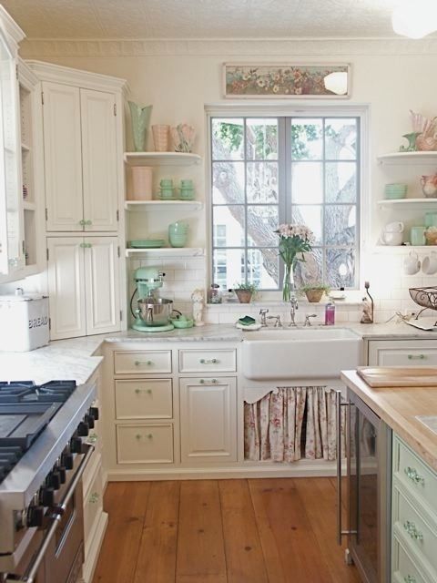 a chic vintage kitchen with white cabinets, a mint green kitchen island, touches of blush and green is a welcoming space