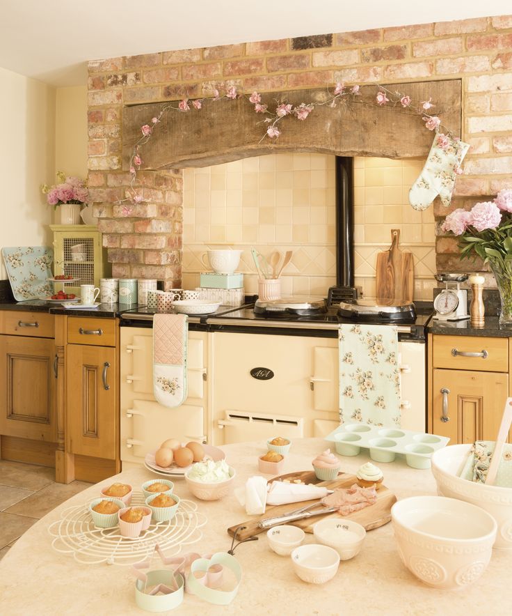 A beautiful vintage kitchen with warm stained cabinets, black coutnertops, a vintage cooker, touches of pink and floral textiles