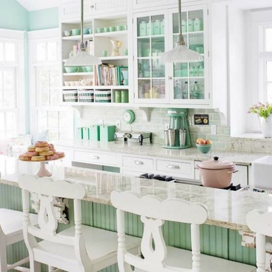 a very chic and cute vintage kitchen done in mint green and white, with glass and open cabinets, a green kitchen island and vintage carved stools is perfect