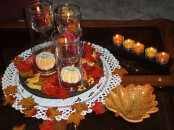 simple fall coffee table decor with candles, fake leaves, fake pumpkins and leaf bowls