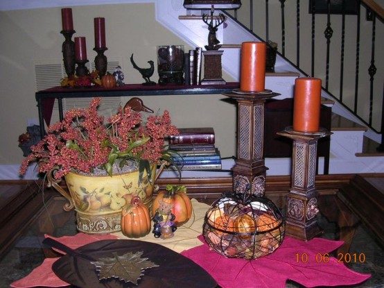 rust candles, fake pumpkins, a bold floral arrangement and leaf bowls for traditional fall coffee table decor