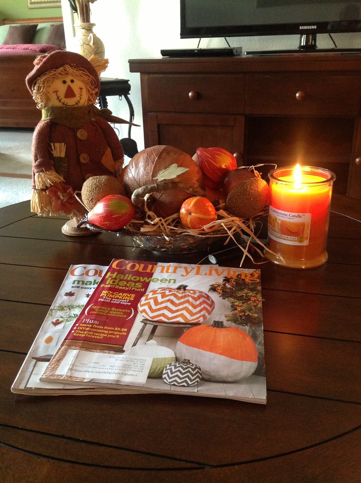A scarecrow, a fall scented candle, a tray with hay and faux pumpkins for a rustic touch in your space