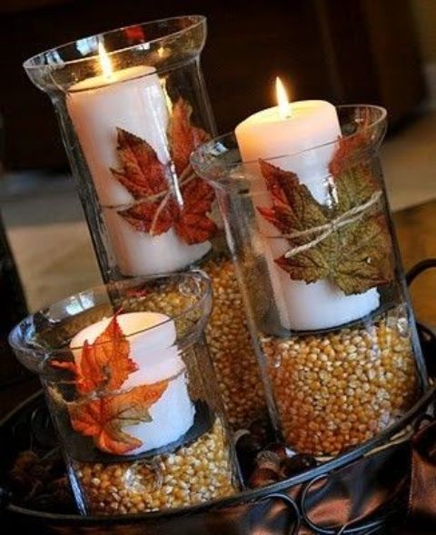a tray with tall candles filled with corn and white candles with leaves attached to them