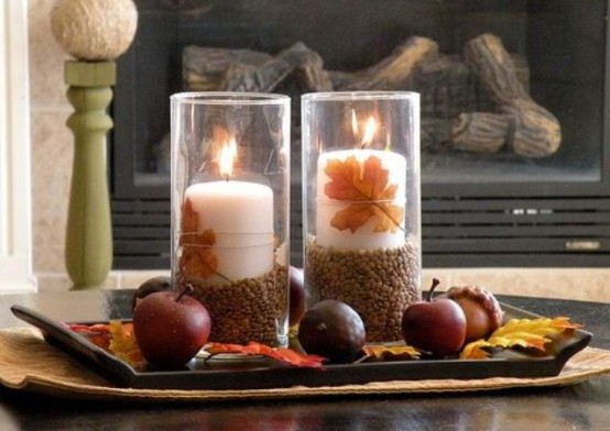 a fall coffee table arrangement with a tray, fall leaves, acorns and apples plus a couple of candles in candle holders