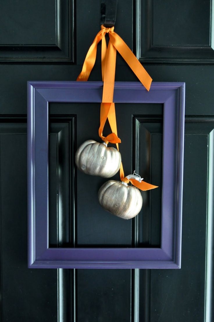 A modern alternative to a fall wreath   a purple frame with metallic pumpkins and orange ribbons is very stylish and bold