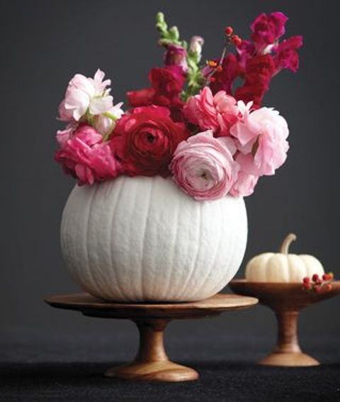a white pumpkin used as a vase for red and light pink blooms will be a bold and gorgeous fall centerpiece
