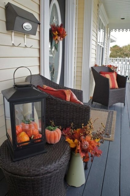 Stuff a lantern with pumpkins and put it on a table on your porch. YOu've got yourself a simple yet stylish seasonal display.
