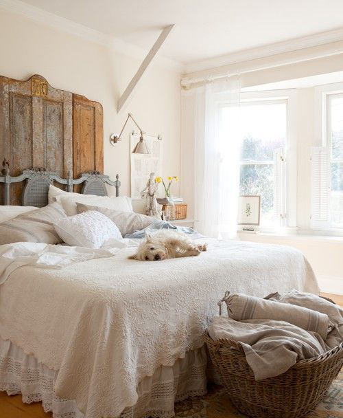 a farmhouse bedroom with a vintage door headboard, a basket for storage and much natural light