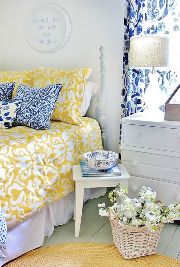 a pastel farmhouse bedroom in blues and yellows, with many prints and whitewashed furniture