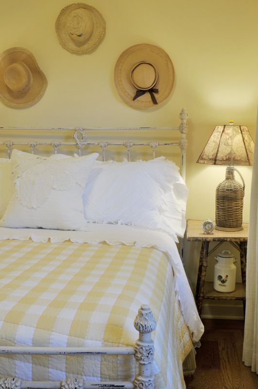 a farmhouse bedroom done in pastels - pastel yellow and blue plus prints and straw hats for decor