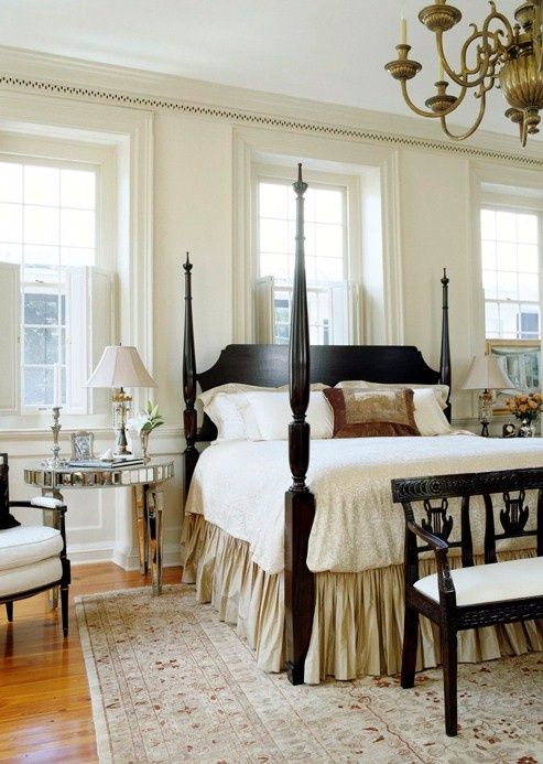 a vintage farmhouse bedroom in neutrals and with dark stained furniture, mirror nightstands and luxurious textiles