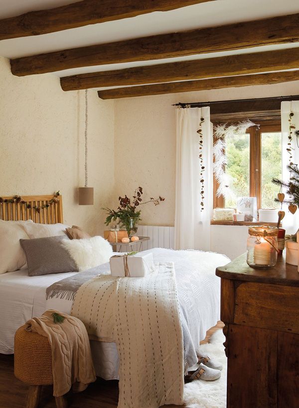 a farmhouse bedroom with wooden beams on the ceiling, hanging lamps and neutral textiles