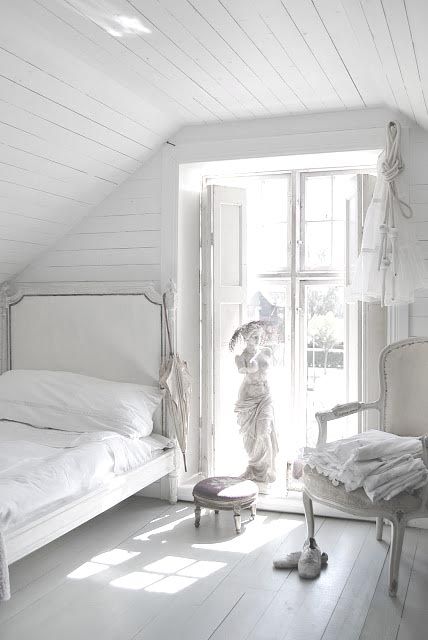 an all-white farmhouse meets vintage bedroom with white wood everywhere, vintage furniture and a sculpture