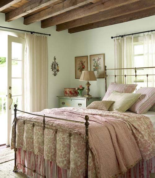 a vintage meets farmhouse bedroom with mint walls, wooden beams on the ceiling and floral print bedding 