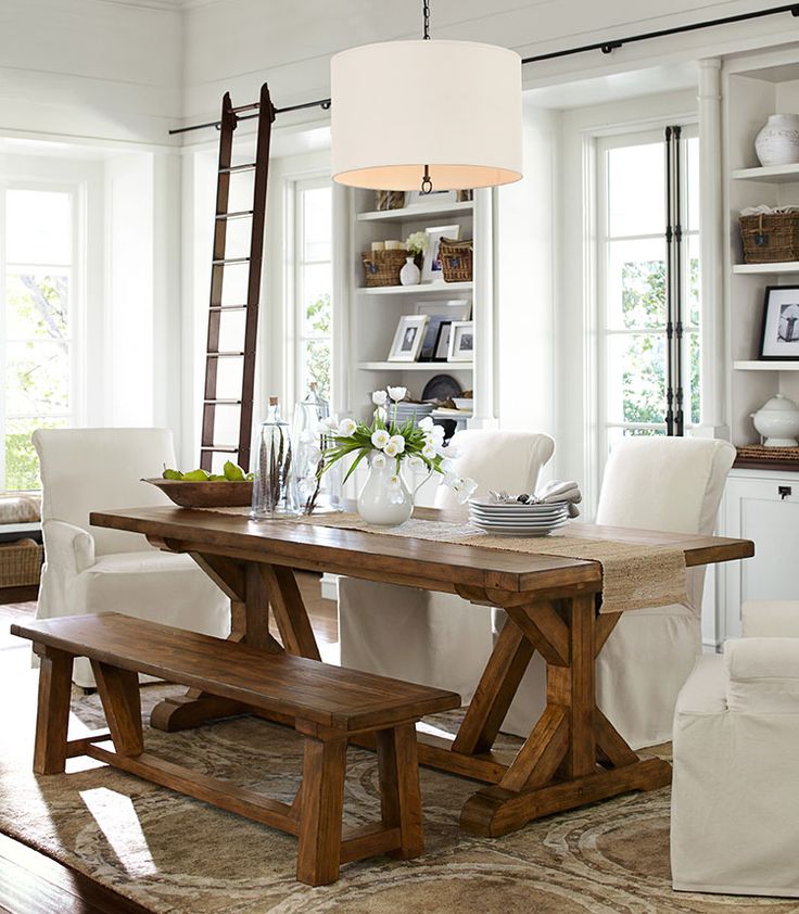 A neutral modern farmhouse dining room with a wooden dining set, some white chairs and built in storage units