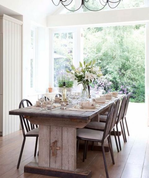 a vintage farmhouse dining area with a vintage dining table and wooden chairs and a view to the garden