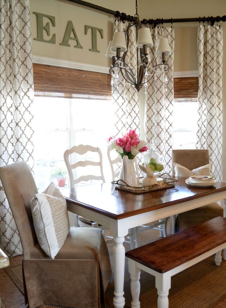 A traditional farmhouse dining room with printed curtains, wicker shades, rustic furniture and leather chairs