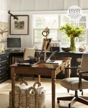 a contrasting farmhouse home office with white walls, black cabinets and desks going along all the walls, a vintage wooden desk,a neutral leather chair and baskets for storage under the desk