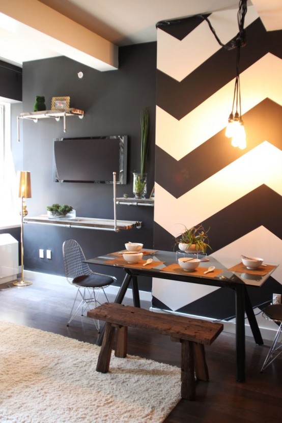 a black and white modern dining space with a statement chevron accent wall, a dining table and benches, a pendant bulb and potted greenery
