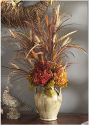 a neutral vase with dried grasses and bright faux blooms is a stylish fall centerpiece or decoration