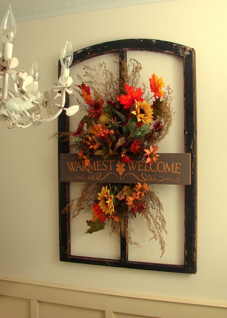 A vintage inspired faux flower decoration with twigs, grasses and leaves in a frame and with a sign