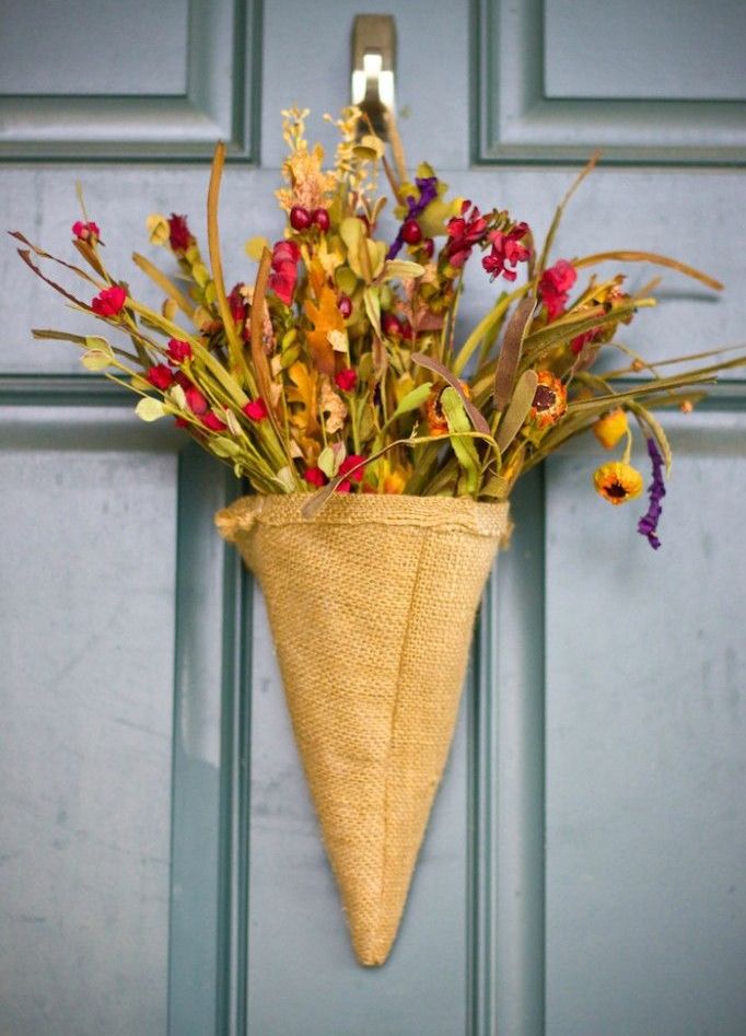 A rustic door arrangement of a burlap cone, faux blooms and greenery is a nice alternative to a usual door wreath