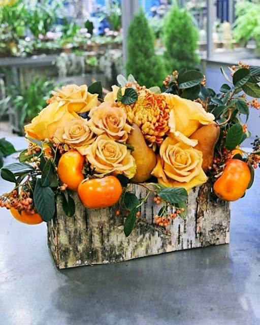 a bright fall centerpiece of a birch bark box with greenery, faux orange roses and fruits is a refined rustic piece
