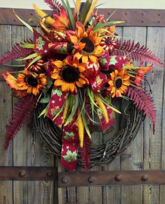 a fall wreath with bright faux blooms, leaves and ribbons is a stylish and long-lasting outdoor decoration with a rustic feel