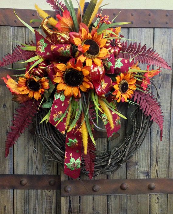 A fall wreath with bright faux blooms, leaves and ribbons is a stylish and long lasting outdoor decoration with a rustic feel