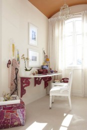 a girlish home office in neutrals, with some boho touches, a floating desk with pink touches, a bright fuchsia ottoman, bold textiles and jewelry