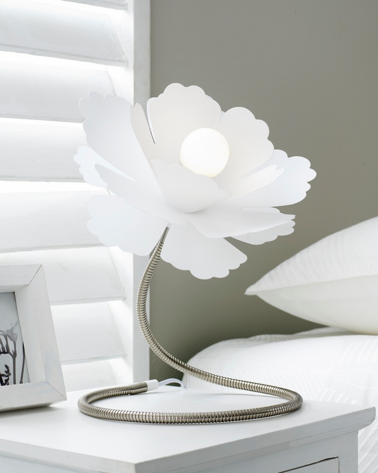 A white flower shaped table lamp of metal with a large lampshade is a creative addition to a bedroom