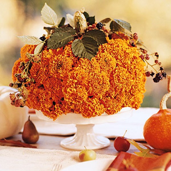 A bold floral arrangement of orange blooms, berries and greenery is a pretty fall or Thanksgiving centerpiece