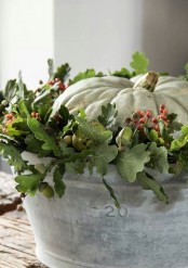 a bucket with greenery, berries and a white pumpkin will make up a cool Thanksgiving centerpiece or decoration