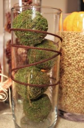 a tall vase with moss balls and twine wrapping it is an east fall or Thanksgiving decoration to rock