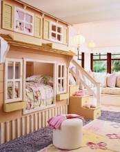 a pastel kid’s room with a house-shaped bed, layered rugs, a pouf and some sofas and seats