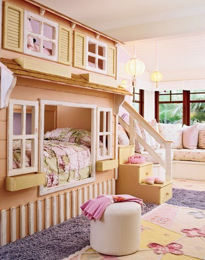 a pastel kid's room with a house-shaped bed, layered rugs, a pouf and some sofas and seats