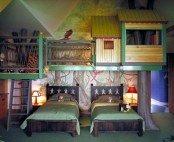 a catchy shared kid’s room with painted trees, an indoor treehouse for playing and two dark carved wooden bed with bright bedding