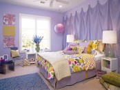 a lilac kid’s room with a curtain headboard, a lilac bed with colorful bedding, floral artwork and a paper pendant lamp