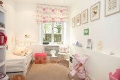 a neutral kid’s room with a cozy white bed with pink bedding, a dollhouse and other toys, printed textiles and some artwork is amazing and very welcoming