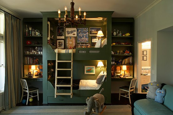A moody green kid's room with a built in bunk bed with lights and shelves, studying spaces, a sofa and some striped textiles